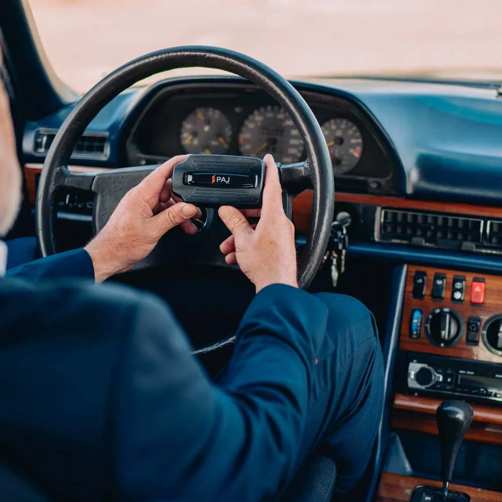 Man holding gps car tracking devices while sitting inside the driver seat of his car.